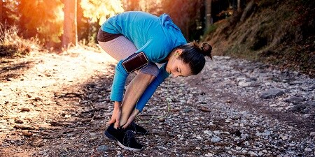 Eine Frau überprüft beim Laufen ihren Knöchel
