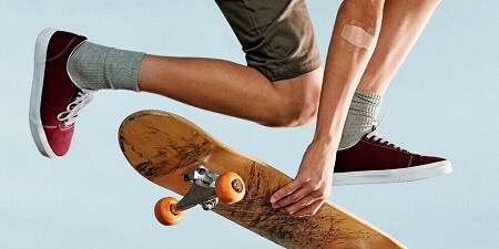 Ein Junge auf einem Skateboard mit einem Pflaster am Ellbogen
